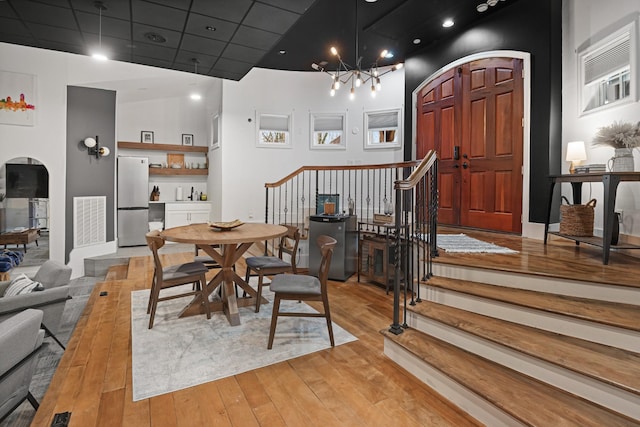 dining area featuring a chandelier, light hardwood / wood-style floors, and a drop ceiling