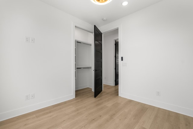 unfurnished bedroom featuring a walk in closet, light hardwood / wood-style flooring, and a closet