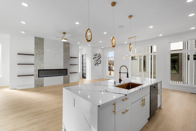 kitchen featuring a spacious island, sink, decorative light fixtures, a fireplace, and white cabinets