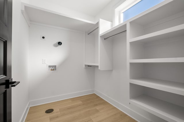 interior space with hookup for a washing machine, light hardwood / wood-style flooring, and hookup for an electric dryer