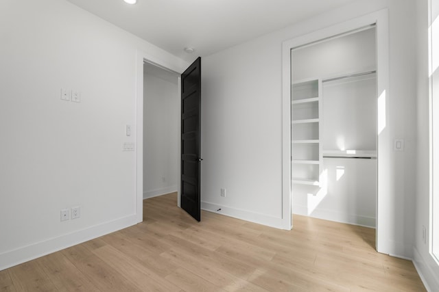 unfurnished bedroom with light wood-type flooring and a closet