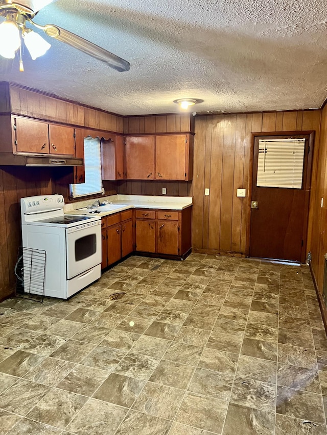 kitchen with a textured ceiling, wooden walls, ceiling fan, and white range with electric stovetop