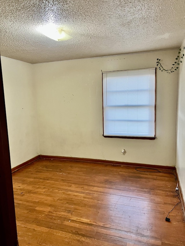 empty room with wood-type flooring and a textured ceiling