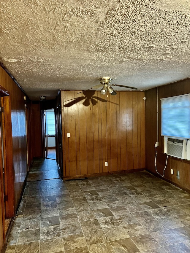 empty room with cooling unit, a textured ceiling, and wood walls