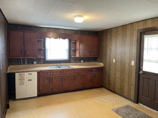 kitchen with dark brown cabinetry, wooden walls, sink, and a wealth of natural light