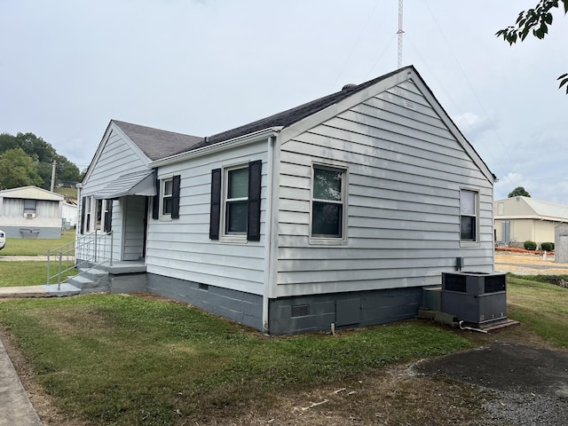 view of side of home with central AC unit and a lawn