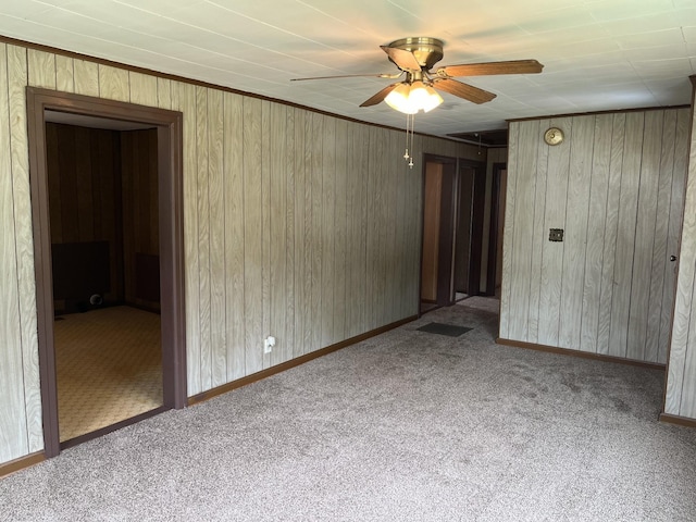 carpeted empty room with wooden walls and ceiling fan