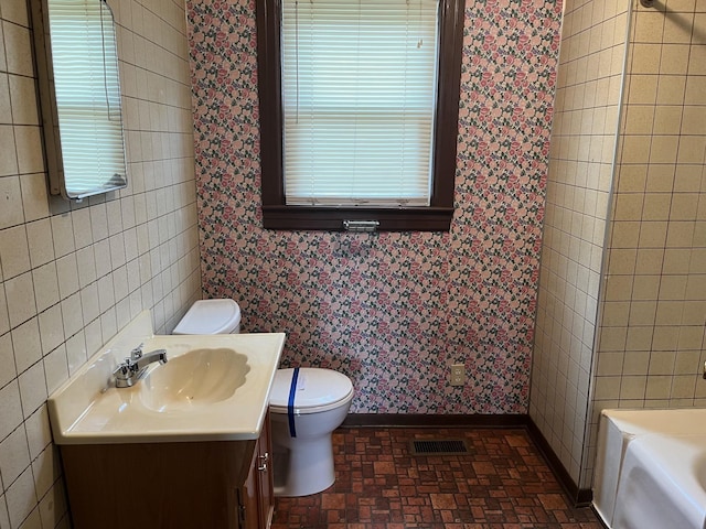 bathroom featuring vanity, a bathtub, and toilet