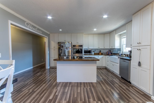 kitchen with stainless steel appliances, white cabinetry, a center island, and dark hardwood / wood-style flooring