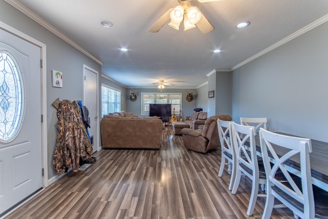 living room with dark wood-type flooring, ornamental molding, and ceiling fan