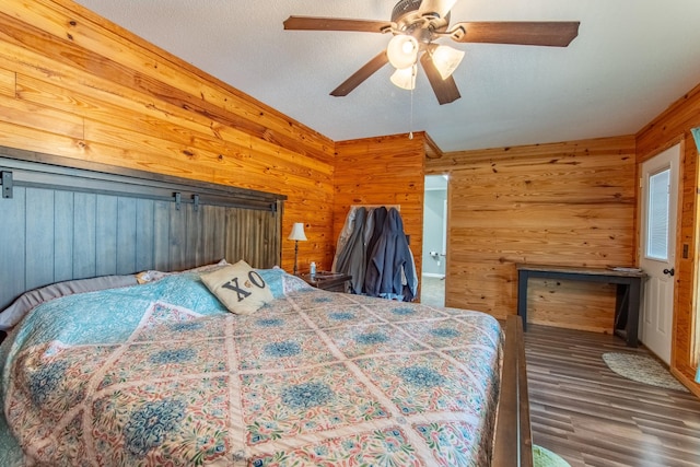 bedroom with ceiling fan, dark hardwood / wood-style flooring, a textured ceiling, and wood walls