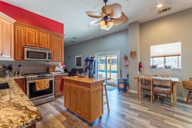 kitchen featuring stainless steel appliances, a center island, a wealth of natural light, and light hardwood / wood-style flooring