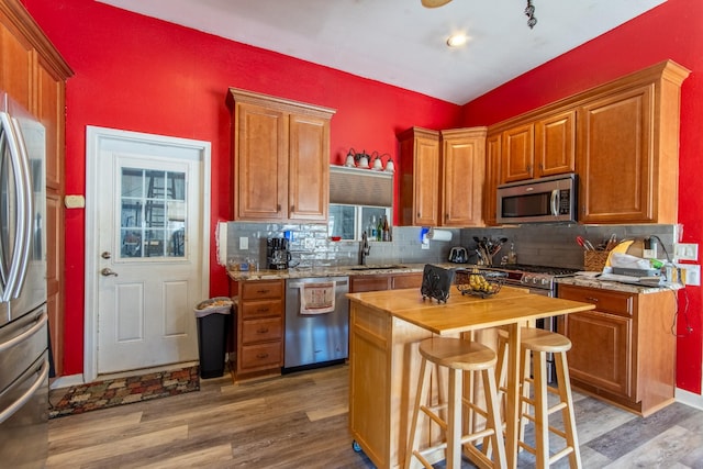 kitchen featuring stainless steel appliances, a kitchen island, sink, and hardwood / wood-style floors