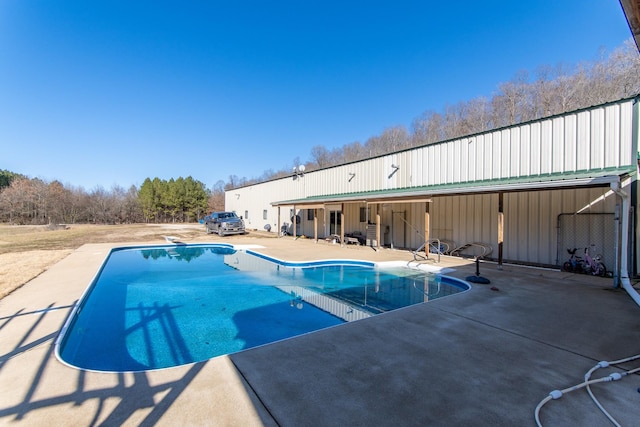 view of swimming pool with a diving board and a patio