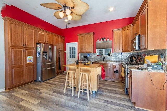 kitchen featuring sink, butcher block countertops, a kitchen island, hardwood / wood-style flooring, and stainless steel appliances