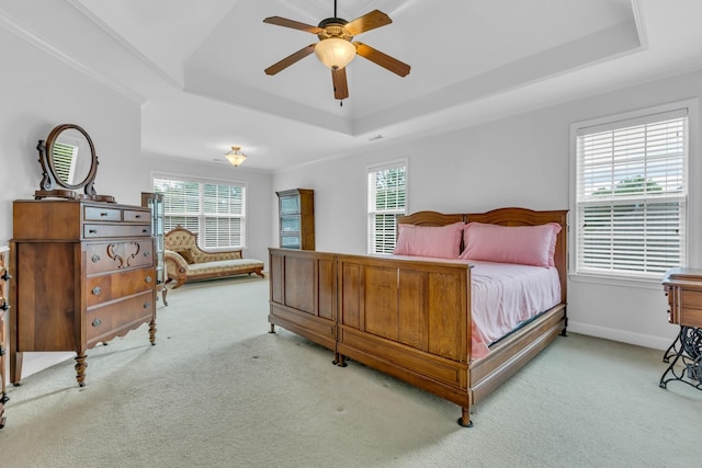 bedroom with multiple windows, light carpet, a raised ceiling, and ceiling fan