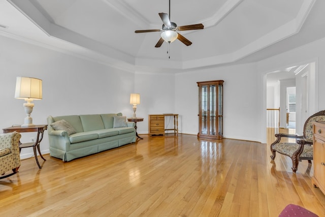 living room featuring light hardwood / wood-style flooring, ceiling fan, and a tray ceiling