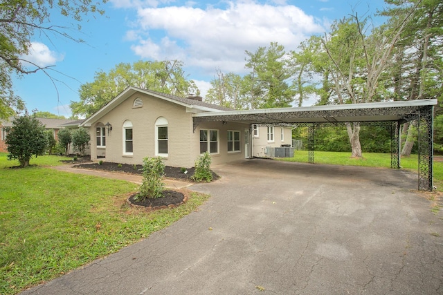 ranch-style house featuring a carport, central AC, and a front lawn