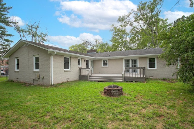 rear view of property featuring a wooden deck, a yard, and a fire pit