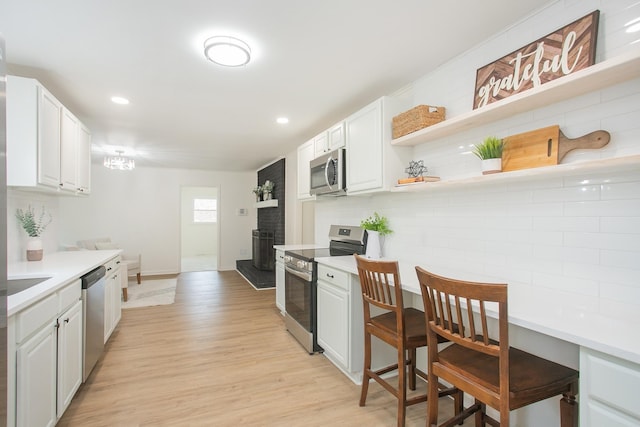 kitchen with decorative backsplash, stainless steel appliances, light hardwood / wood-style flooring, and white cabinets