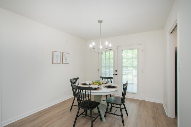 dining room featuring french doors, an inviting chandelier, and light hardwood / wood-style flooring