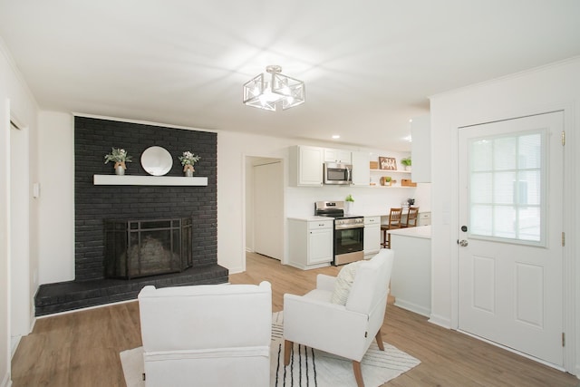 living room featuring crown molding, a fireplace, and light wood-type flooring