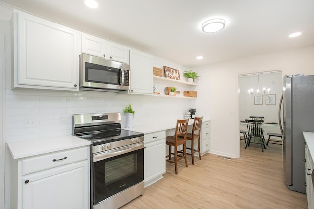 kitchen with stainless steel appliances, tasteful backsplash, white cabinets, and light wood-type flooring