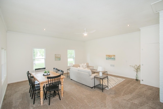 carpeted dining space featuring crown molding and ceiling fan