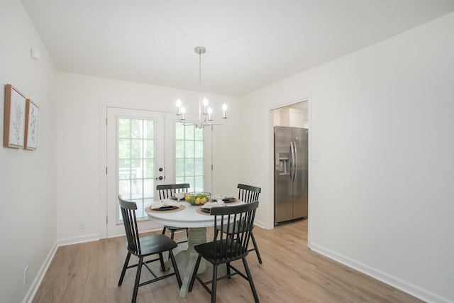 dining space featuring an inviting chandelier, french doors, and light wood-type flooring