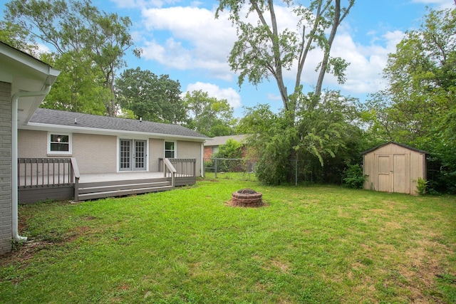 view of yard featuring a storage shed, a deck, and an outdoor fire pit