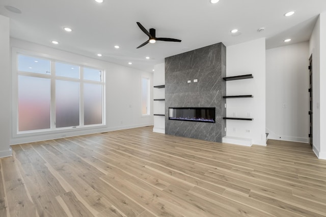 unfurnished living room featuring a fireplace, light hardwood / wood-style floors, and ceiling fan