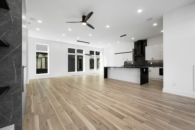 unfurnished living room with sink, ceiling fan, and light hardwood / wood-style flooring