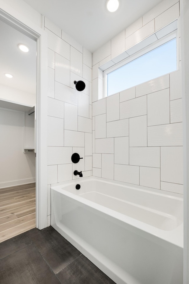 bathroom with hardwood / wood-style flooring and tiled shower / bath