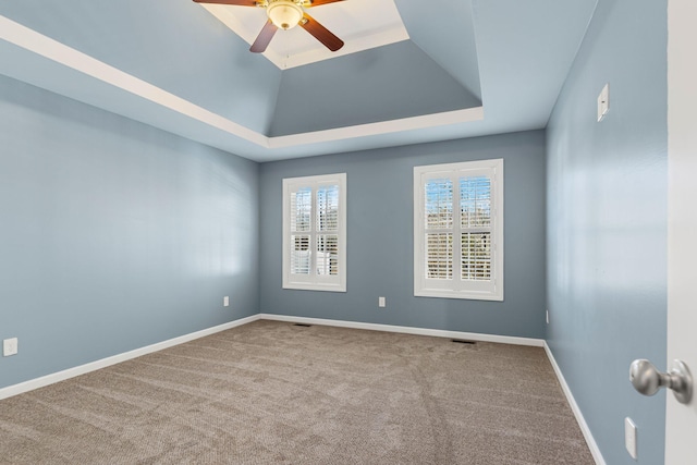 carpeted spare room with ceiling fan and a raised ceiling