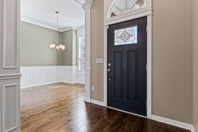 foyer entrance with an inviting chandelier, ornamental molding, dark hardwood / wood-style floors, and ornate columns