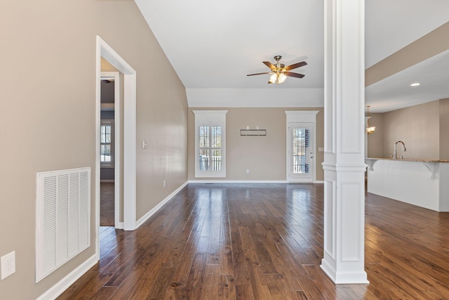 unfurnished living room with decorative columns, dark wood-type flooring, sink, and ceiling fan