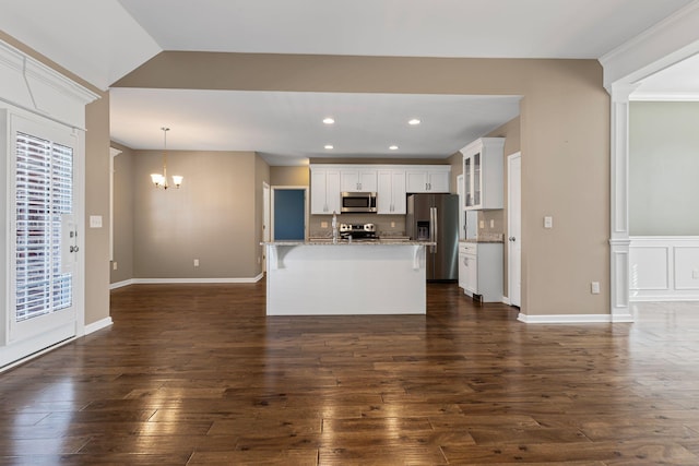 kitchen with white cabinetry, decorative light fixtures, dark hardwood / wood-style floors, an island with sink, and stainless steel appliances