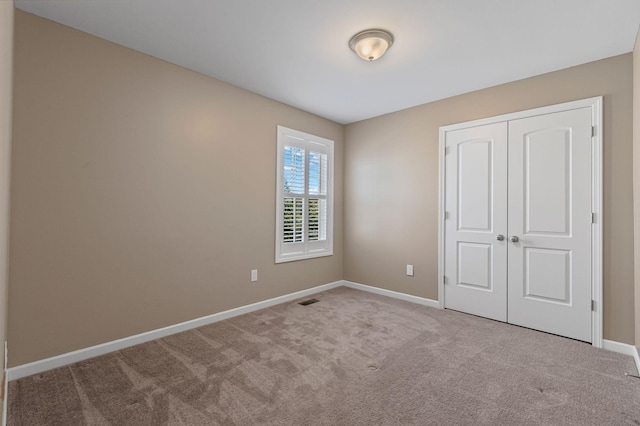 unfurnished bedroom with a closet and light carpet