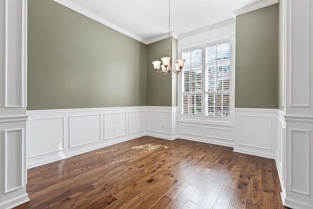 unfurnished dining area featuring decorative columns, dark hardwood / wood-style flooring, crown molding, and an inviting chandelier