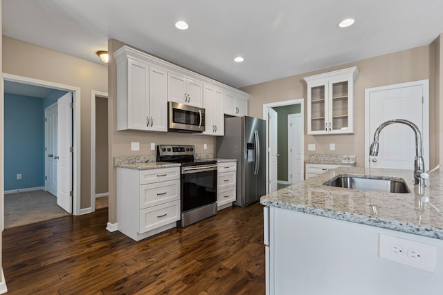 kitchen featuring sink, appliances with stainless steel finishes, dark hardwood / wood-style floors, light stone countertops, and white cabinets