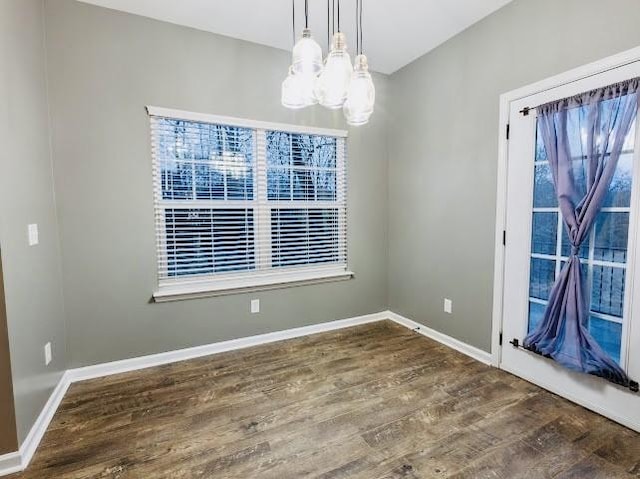 unfurnished dining area with dark wood-type flooring and a chandelier