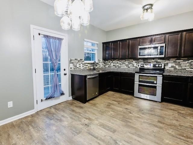 kitchen featuring sink, light stone counters, dark brown cabinetry, stainless steel appliances, and light hardwood / wood-style flooring