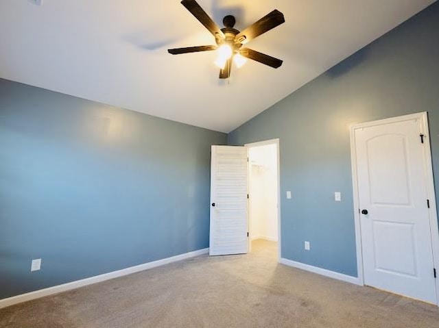 unfurnished bedroom with lofted ceiling, a spacious closet, ceiling fan, light carpet, and a closet