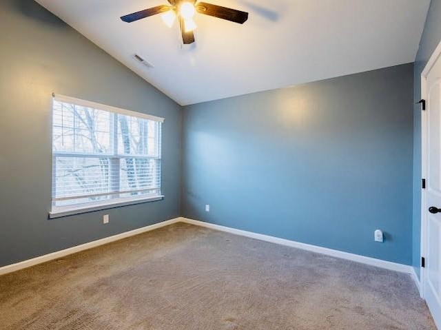 spare room with ceiling fan, vaulted ceiling, and carpet