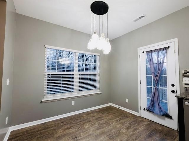 unfurnished dining area featuring dark wood-type flooring and a notable chandelier