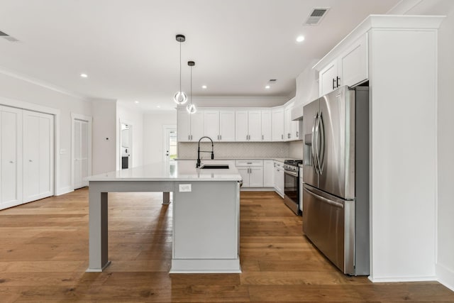 kitchen featuring appliances with stainless steel finishes, pendant lighting, an island with sink, sink, and white cabinets