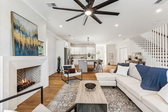 living room featuring crown molding, ceiling fan, and light wood-type flooring