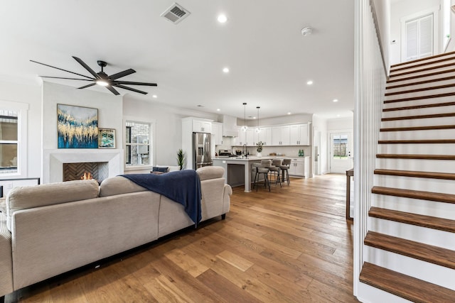 living room with ceiling fan, ornamental molding, sink, and light hardwood / wood-style floors