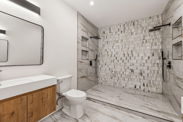 bathroom with vanity, tiled shower, and toilet