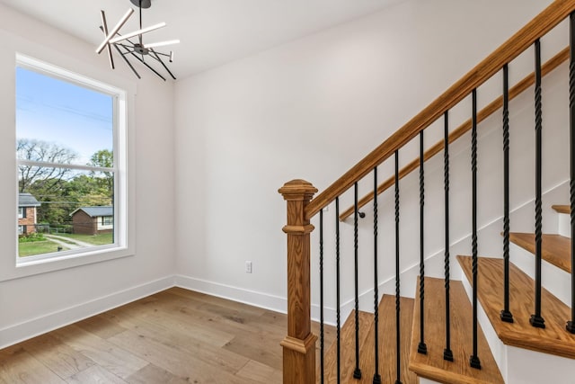 stairs with an inviting chandelier and hardwood / wood-style flooring